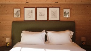 A well-organized bedroom showcases a cozy bed, two side tables with lamps, and portraits above.