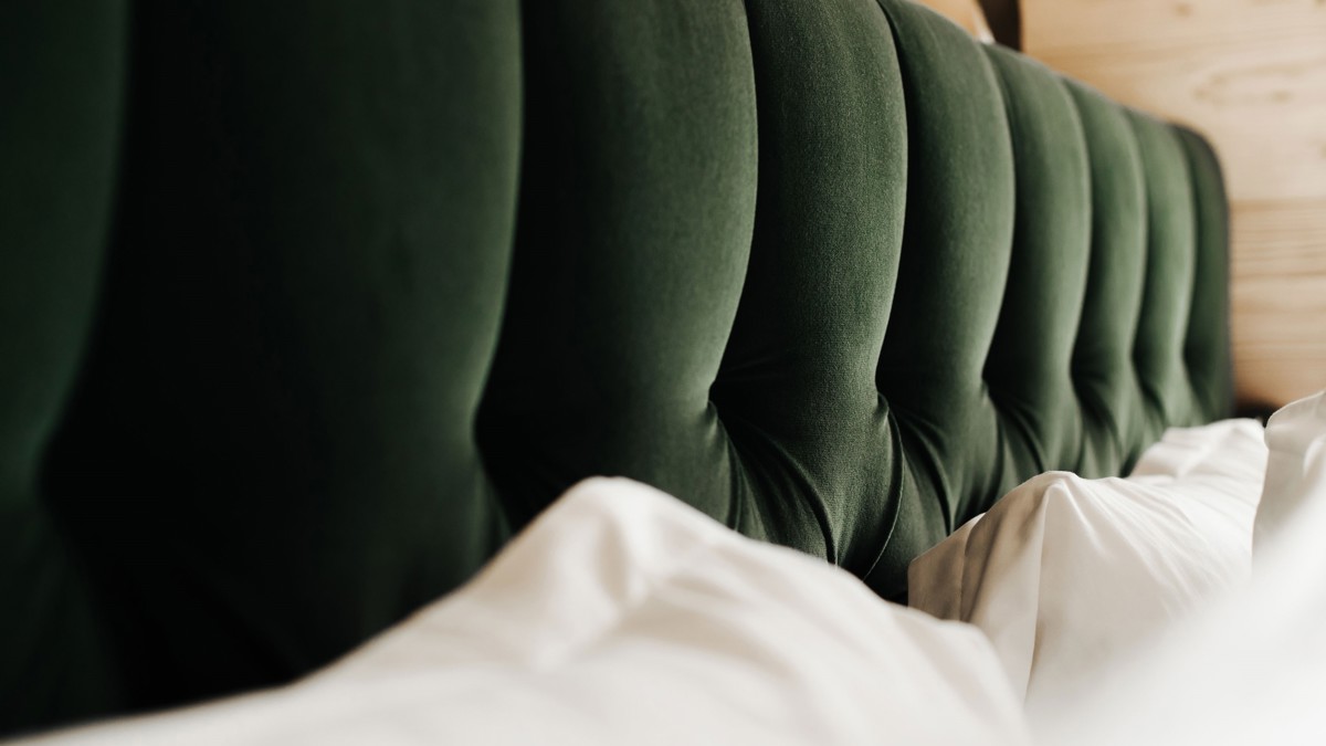 A clicked photo of the dark green-colored bed’s headboard looks absolutely amazing.