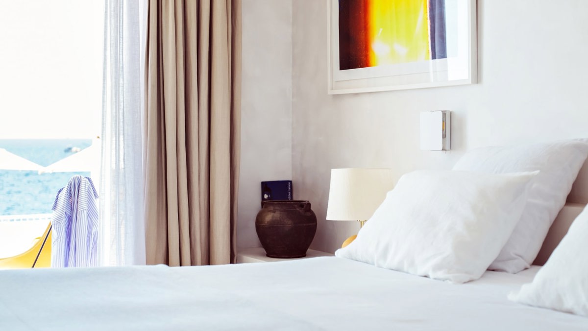 A well-organized bedroom features a cozy bed, with beautifully mounted portraits above the headboard.