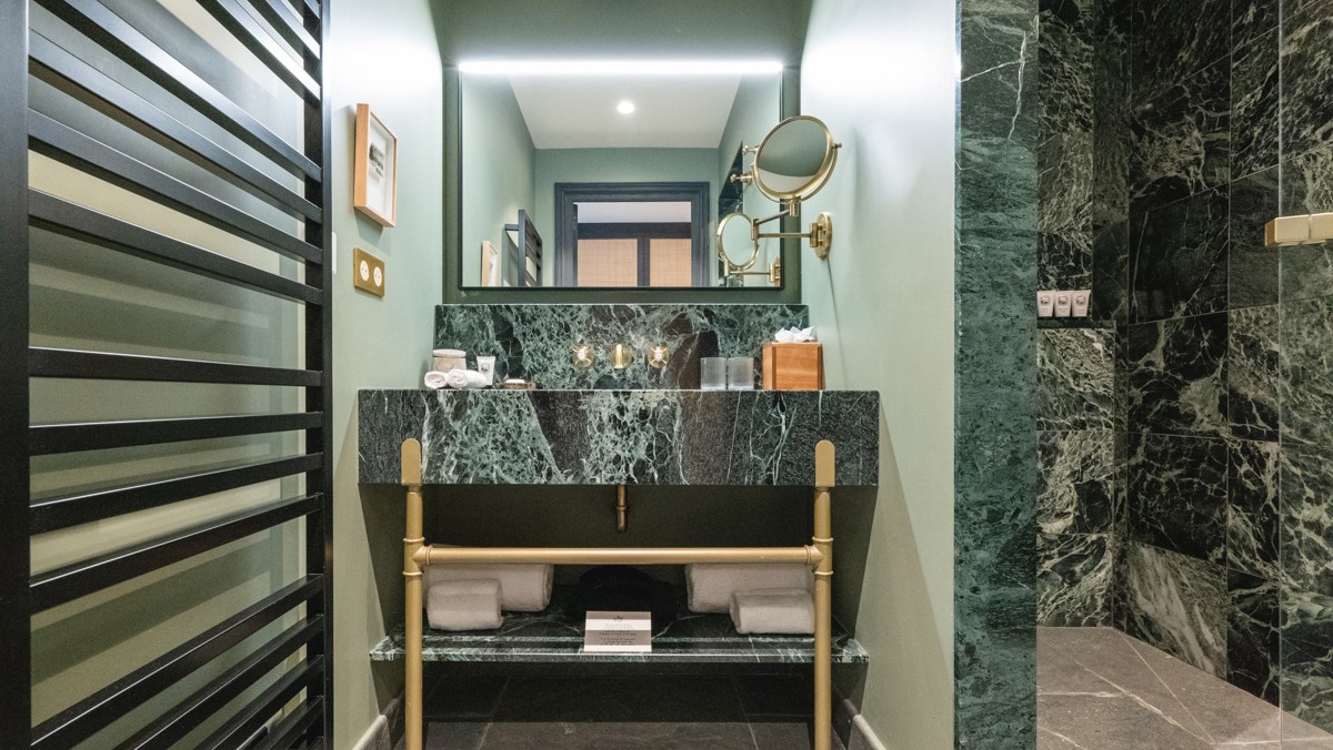 A green-tiled bathroom is captured, displaying all essentials neatly organized and properly arranged.