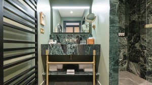 A green-tiled bathroom is captured, displaying all essentials neatly organized and properly arranged.