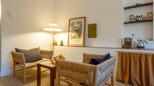 Une paire de chaises confortables avec une table dans le coin et un portrait à côté du lampadaire.