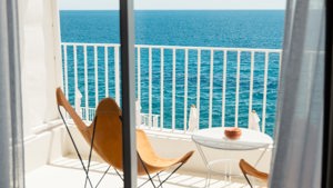 A wonderful ocean view is visible through the balcony glass, with a chair and table placed outside.