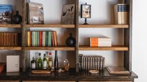 Some notebooks are properly arranged on the shelves along with decorative items and wine bottles.