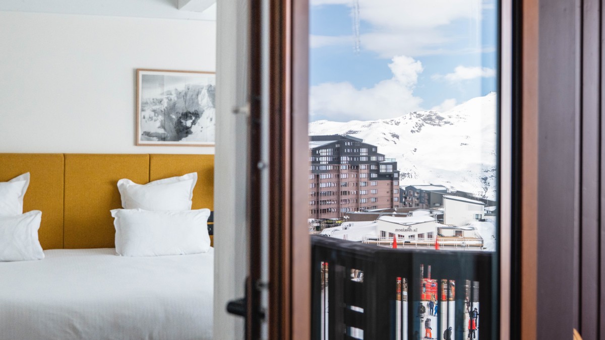 A portrait is mounted above the bed, with the snowy city’s reflection in the window.