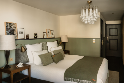 Chambre du Fitz Roy à Val Thorens, lambris vert sauge, linge blanc, plaid olive et lustre en verre de Murano