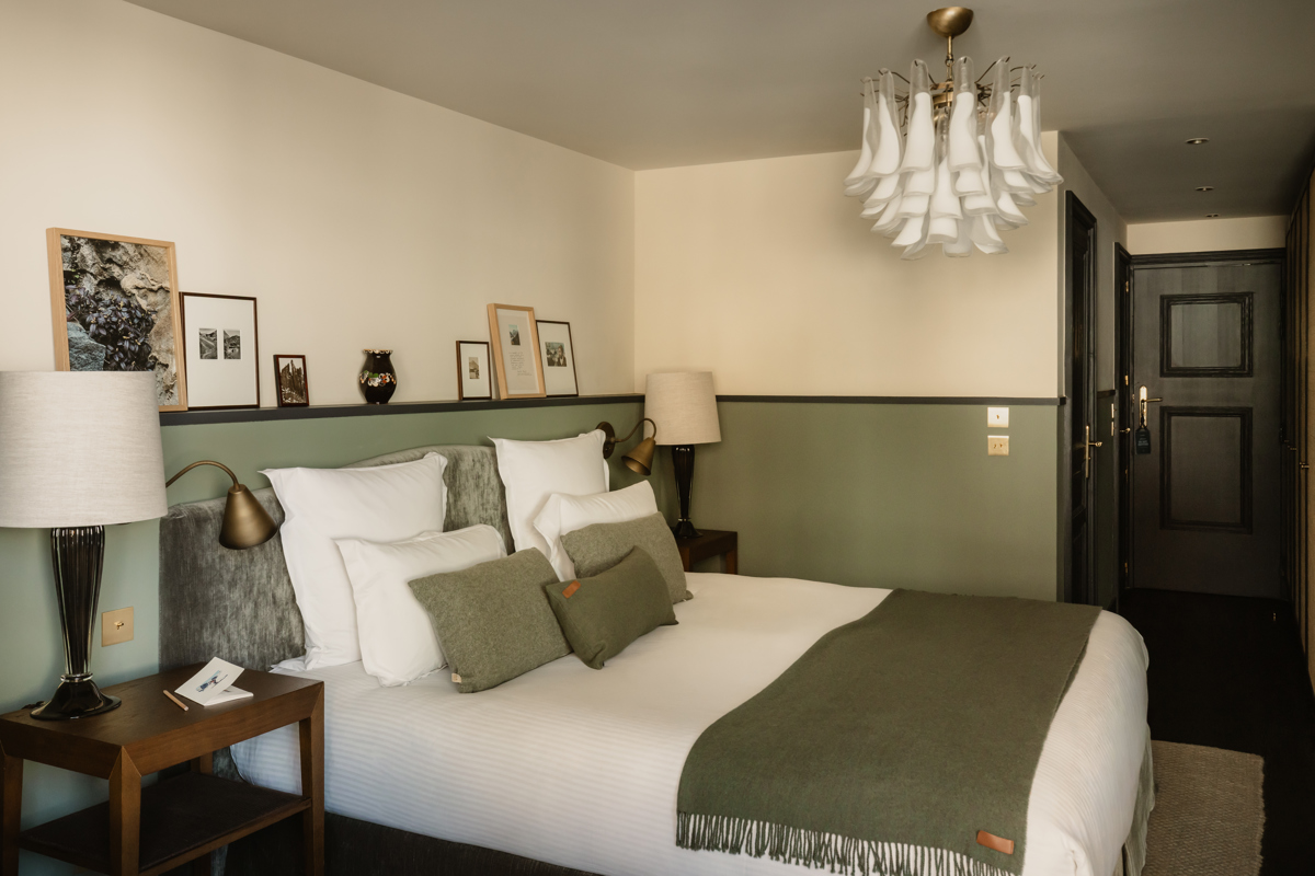 Chambre du Fitz Roy à Val Thorens, lambris vert sauge, linge blanc, plaid olive et lustre en verre de Murano