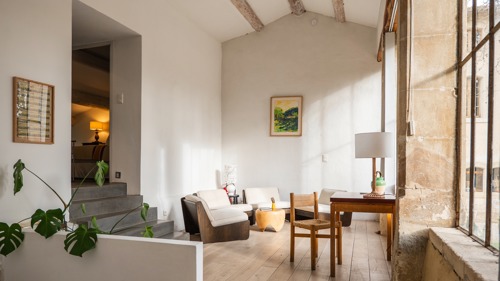 Espace de vie organisé avec canapé confortable, table basse, chaise, lampe et portrait.
